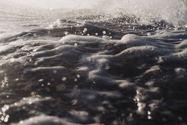 Moody close up of white water and ripples on ocean surface at dusk - CAVF64470