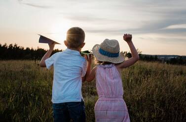 Brother and sister looking into the distance playing at sunset - CAVF64539