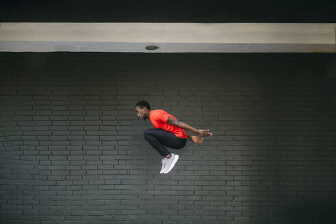 Junger sportlicher Mann, der vor eine Mauer springt - OCMF00764