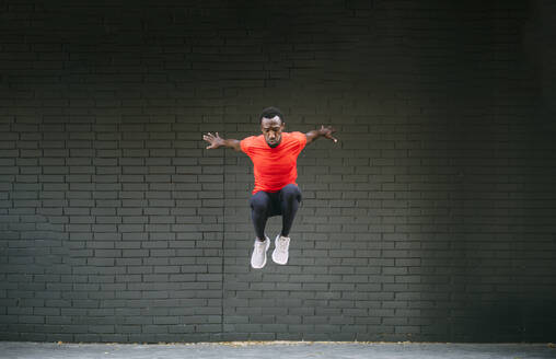 Junger sportlicher Mann, der vor eine Mauer springt - OCMF00770