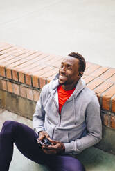 Young sportive man taking a break from workout using his smartphone - OCMF00773