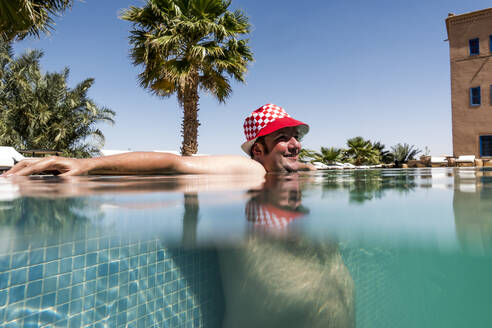 Übergewichtiger Mann mit Hut beim Baden im Pool - OCMF00780