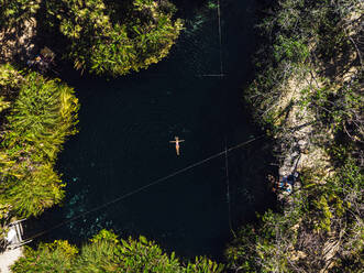 Von oben: Frau mit ausgestreckten Armen genießt das Bad in der sauberen Cenote - CAVF64650