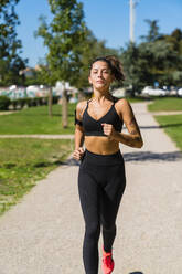 Porträt einer jungen Frau, die in einem Park läuft - MGIF00746