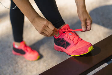 Close-up of sportive young woman tying her shoes - MGIF00751