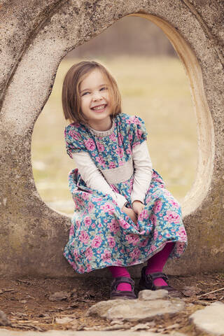 Porträt eines lachenden kleinen Mädchens in einem Kleid mit Blumenmuster, lizenzfreies Stockfoto