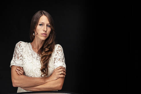 Portrait of young woman with arms crossed against black background - WFF00114