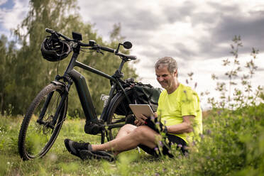 Älterer Mann mit digitalem Tablet während seiner Radtour mit einem E-Bike - BFRF02094