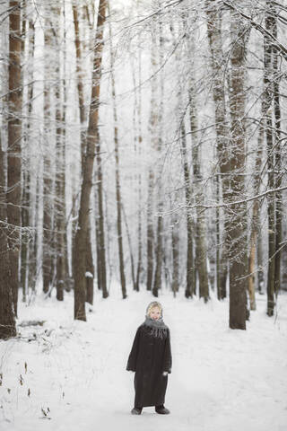 Lächelndes kleines Mädchen vor einem Winterwald, lizenzfreies Stockfoto