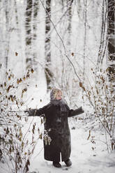 Kleines Mädchen mit Mantel im Winterwald stehend - EYAF00499