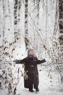 Kleines Mädchen mit Mantel im Winterwald stehend - EYAF00499