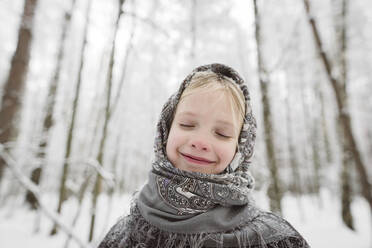 Porträt eines glücklichen kleinen Mädchens mit Kopftuch im Winterwald - EYAF00503