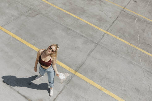 Junge Frau steht auf einem Parkplatz - LHPF01003