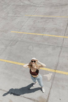 Lächelnde junge Frau auf einem Parkplatz - LHPF01004