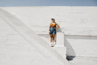 Young woman standing in front of a white wall outdoors - LHPF01006