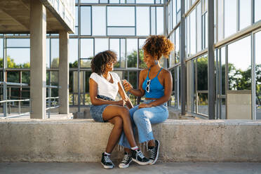 Two friends sitting together on a wall having fun - MPPF00059