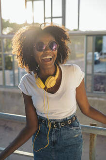 Portrait of laughing young woman with sunglasses and headphones - MPPF00073