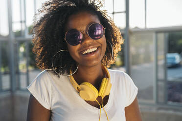 Porträt einer glücklichen jungen Frau mit Kopfhörern und Sonnenbrille - MPPF00074