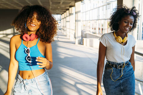 Portrait of two young women with headphones during sunset stock photo