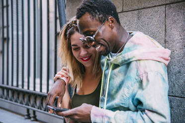 Lächelndes Paar benutzt Mobiltelefon im Freien - CJMF00048