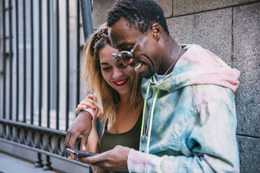 Smiling couple using cell phone outdoors - CJMF00048