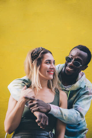 Porträt eines glücklichen Paares vor einer gelben Wand, lizenzfreies Stockfoto