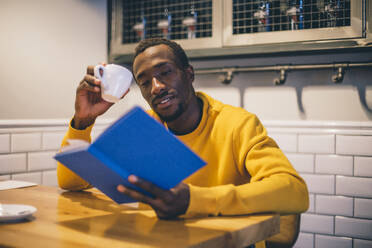Porträt eines Mannes in einem Café, der ein Buch liest - CJMF00064