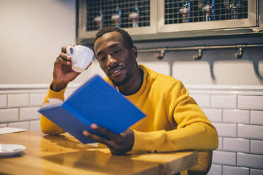 Portrait of man in a coffee shop reading a book - CJMF00064