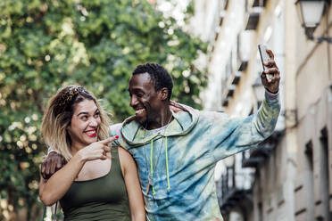 Portrait of laughing couple taking selfie with smartphone, Madrid, Spain - CJMF00065