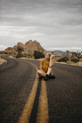 Frau sitzt auf der Straße, Joshua Tree National Park, Kalifornien, USA, lizenzfreies Stockfoto