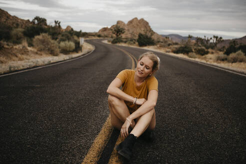 Woman sitting on road, Joshua Tree National Park, California, USA - LHPF01013