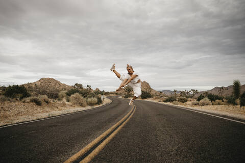 Woman jumping on road, Joshua Tree National Park, California, USA stock photo