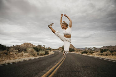 Frau springt auf Straße, Joshua Tree National Park, Kalifornien, USA - LHPF01017