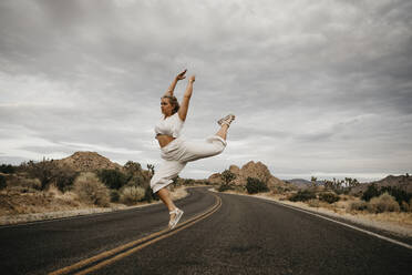 Frau springt auf Straße, Joshua Tree National Park, Kalifornien, USA - LHPF01018