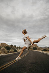 Frau springt auf Straße, Joshua Tree National Park, Kalifornien, USA - LHPF01020