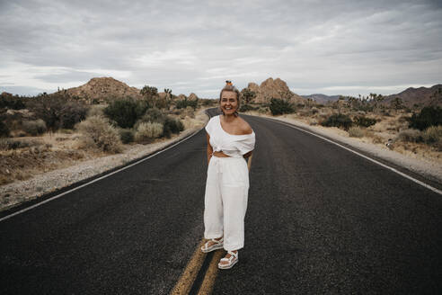 Glückliche Frau auf der Straße stehend, Joshua Tree National Park, Kalifornien, USA - LHPF01022