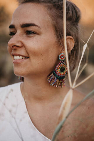 Porträt einer lächelnden Frau mit Ohrring und Zweigen, Joshua Tree National Park, Kalifornien, USA, lizenzfreies Stockfoto