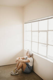Young woman sitting on the floor in a room - LHPF01029