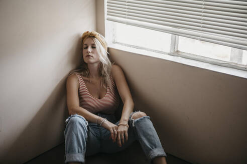 Young woman sitting on the floor in a room - LHPF01038