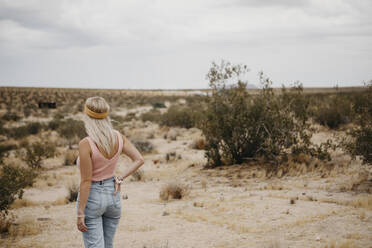 Young woman standing in desert landscape, Joshua Tree National Park, California, USA - LHPF01043