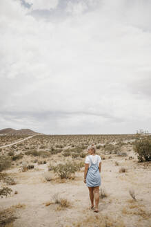 Junge Frau geht durch Wüstenlandschaft, Joshua Tree National Park, Kalifornien, USA - LHPF01050