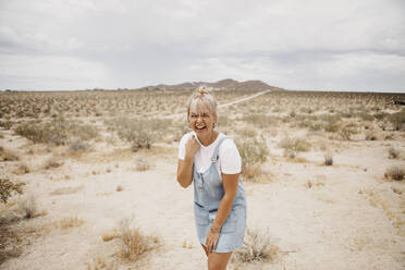 Porträt einer lachenden jungen Frau in einer Wüstenlandschaft, Joshua Tree National Park, Kalifornien, USA - LHPF01054