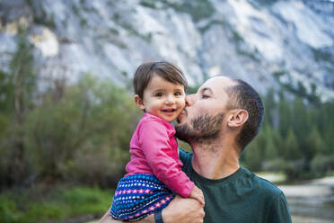 Portrait of happy baby girl kissed by her father, Yosemite National Park, California, USA - GEMF03204