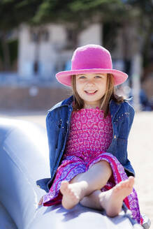 Porträt eines modischen kleinen Mädchens, das auf einem Schlauchboot am Strand sitzt - XCF00276