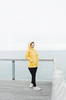 Young woman wearing yellow rain coat - NAF00118