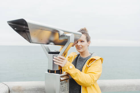 Young blond woman looking through telescope - NAF00125