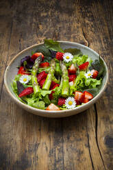Nahaufnahme von Salat mit grünem Spargel, Erdbeeren und Gänseblümchen - LVF08318