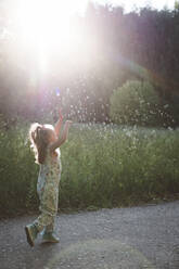 Kleines Mädchen fängt Seifenblasen im Sonnenschein - EYAF00531
