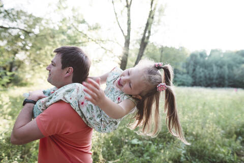 Vater trägt verspielte Tochter auf seinen Schultern, lizenzfreies Stockfoto