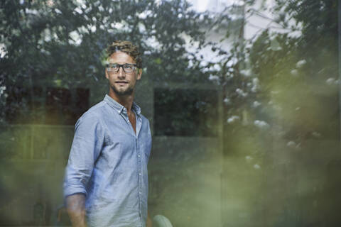 Casual young businessman behind windowpane in office stock photo